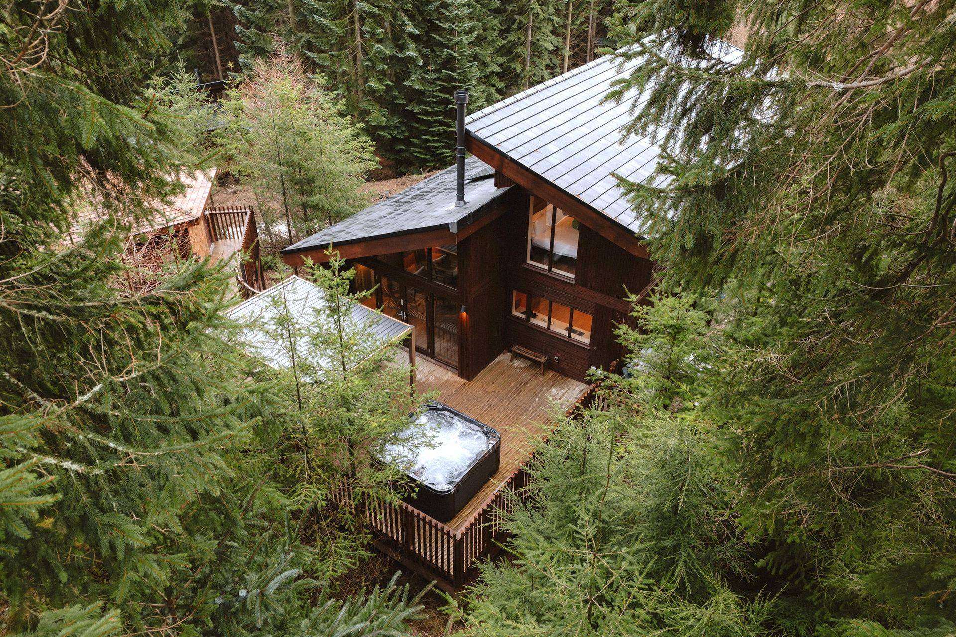 Domek North Peak Cabins o zmierzchu, z jacuzzi na tarasie, otoczony lasem